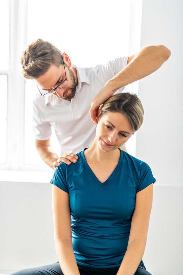 Physical therapist stretching neck of patient